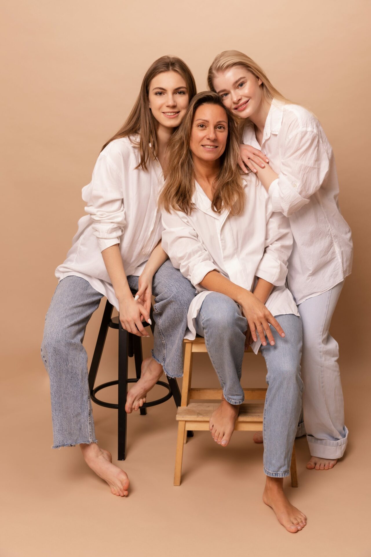 three-caucasian-women-different-ages-white-shirts-jeans-look-camera-beige-background-concept-relatives